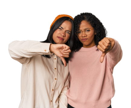 Young Latin friends together in studio showing thumb down and expressing dislike.