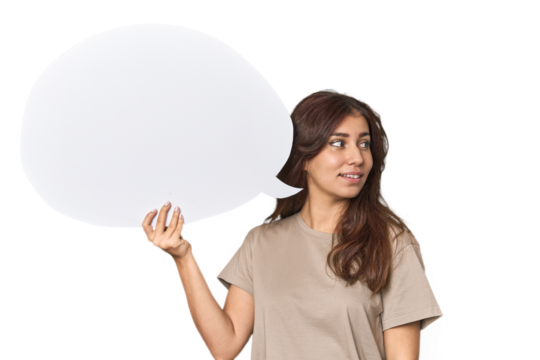 Middle Eastern woman holding comic bubble looks aside smiling, cheerful and pleasant.