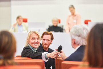 Female speaker asking audience in business event at auditorium
