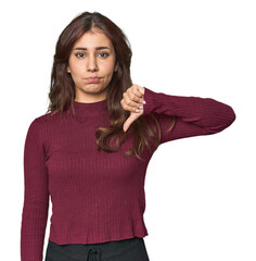 Middle Eastern woman in studio showing a dislike gesture, thumbs down. Disagreement concept.