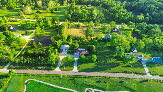 Golf course country club in rural area with low density housing, lush greenery trees large acreage, meadows and farm houses near back road in agricultural area, peaceful Midwest, aerial view