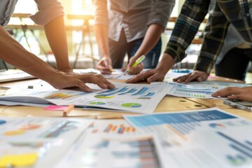 The business team is pointing at the data and graphs on documents in an office.