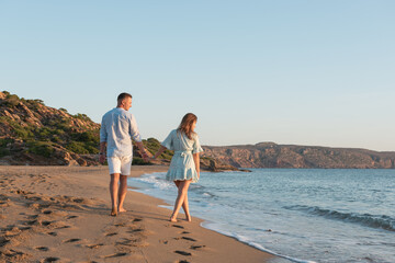 Happy couple is walking on the beach during sunset or sunrise. Summer vacations.