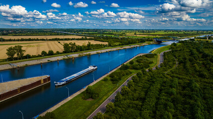 Fototapeta premium Aerial view of a bargeboat navigates an industrial waterway.