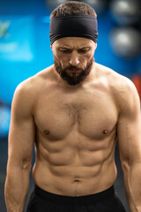 Sexy, bearded man, athlete with naked pumped up muscular torso training in gym
