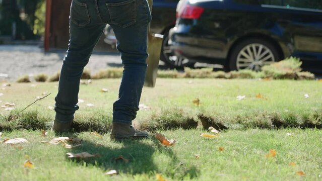 Slow motion of a construction worker digging in grassy area with a shovel