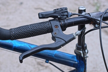 part of a black metal bicycle handlebar with a handbrake and a plastic handle in the street