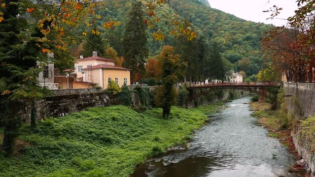 Riverfront buildings and Podul de Fonta on River Cerna on a cloudy day in Baile Herculane, Romania
