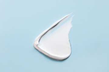 White smear of cream, mask or balm on a blue background. The texture of the skin or hair care product.