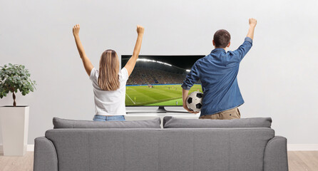 Rear view shot of ayoung man and woman watching a football match on tv
