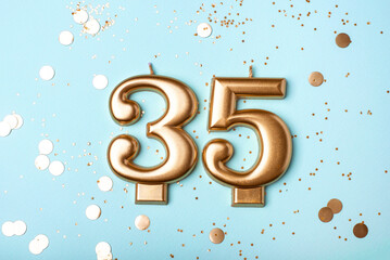 35 years celebration. Greeting banner. Gold candles in the form of number thirty five on blue background with confetti.