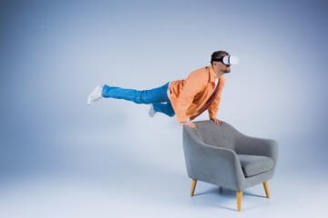 A man in an orange shirt executes a mesmerizing trick on a chair in a studio setting, showcasing...