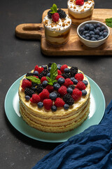 Homemade cake with fresh berries and sweet desserts on dark background.