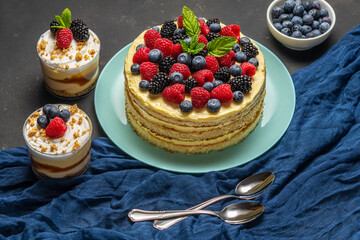 Homemade cake with fresh berries and sweet desserts on dark background.