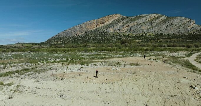 Aerial view of woman hiking in vast, rugged mountain terrain, Embalse de Guadalteba, Campillos, Andalusia, Spain.