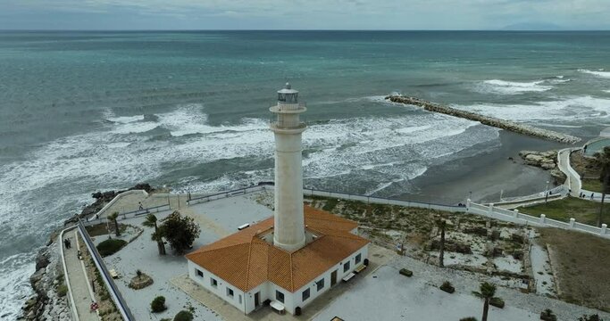 Aerial view of Torrox Lighthouse and coastal town with Mediterranean shore and crashing waves, Andalusia, Spain.