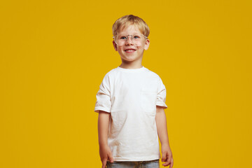 Little adorable kid wearing stylish eyeglasses and white t-shirt. Cute boy looking away and smiling...