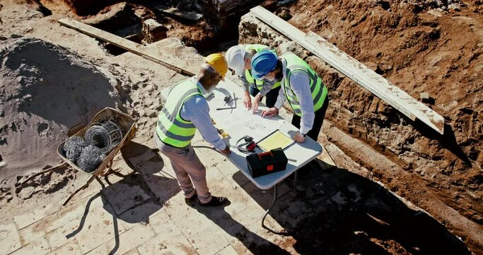 Team, architects and blueprint of building, construction or digging site for planning foundation of mining infrastructure safety. Group, engineer and excavation design of project development progress
