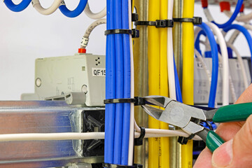 Cutting the cable tie on the insulated mounting wire in the electrical panel.