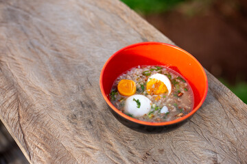 Selective focus Thai style minced pork porridge with boiled egg. Breakfast in an orange cup Helps increase energy