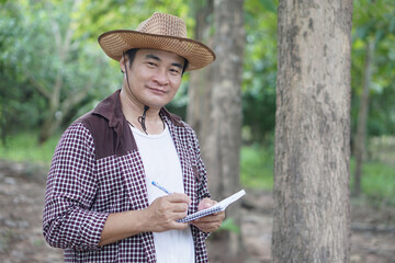 Handsome Asian man botaninst holds paper notebook to survey bonical plants in forest....