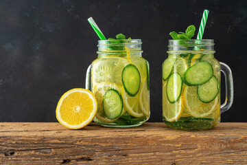 Detox water with sliced lemon and cucumber in a jar on dark background. Healthy concept.
