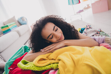 Portrait of nice young woman closed eyes lay messy comfy pile stack clothes flat indoors