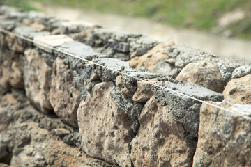 Unfinished rough stone wall in outdoor. Construction