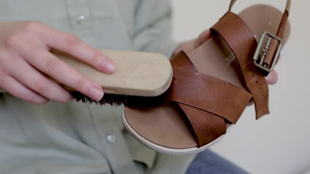 Brushing leather nubuck sandals. Cleaning shoes from dust and dirt. close up