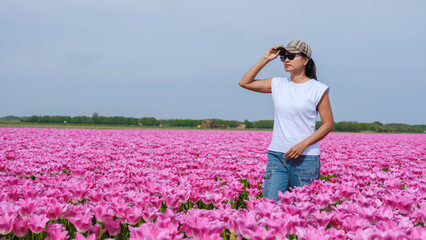 A woman stands gracefully in a field of vibrant pink tulips, surrounded by natures beauty in Texel,...
