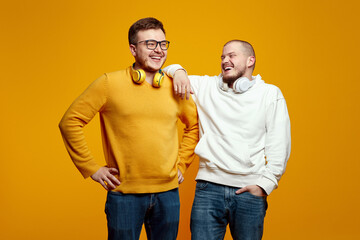 Two handsome young men guys friends with headphones wearing casual outfit, laughing and having fun...