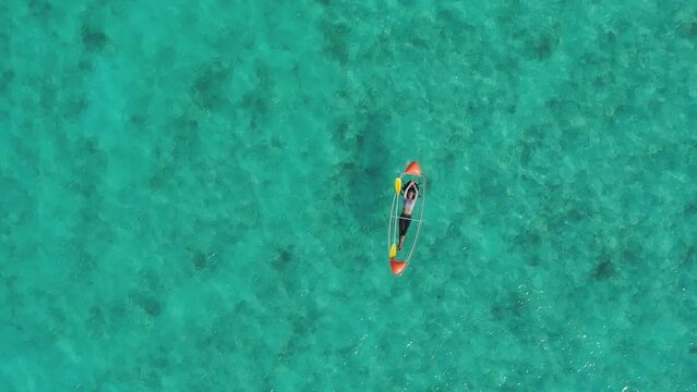 Aerial view of woman relaxing on a glass boat in clear turquoise water, Thoddoo, Maldives.