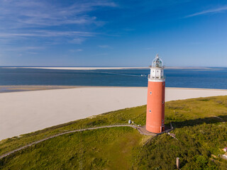 An aerial view captures a majestic lighthouse perched on a sandy beach in Texel, Netherlands,...