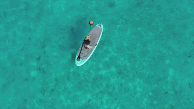 Aerial view of tranquil yoga and paddleboarding on turquoise waters, Thoddoo, Maldives.