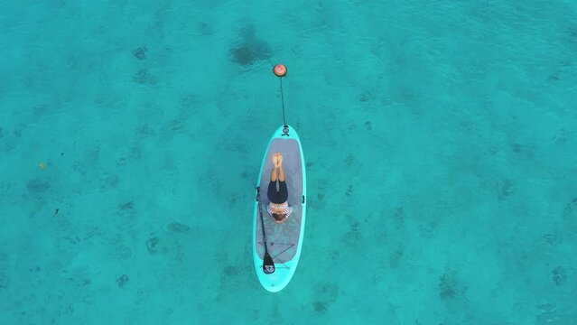 Aerial view of serene paddleboarding in crystal clear waters, Thoddoo, Maldives.