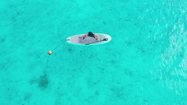 Aerial view of turquoise waters with paddle boarder in Thoddoo, Maldives.