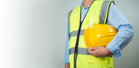 Civil engineer architect standing holding a safety helmet on grey background, Construction site plans to build high-rise buildings, Engineer building concept, Background for construction.