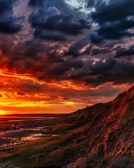 Fiery Sunset Over Rugged Coastline, an awe-inspiring natural display, concept for dramatic...