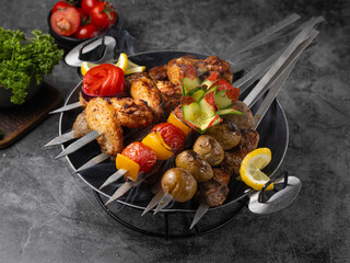 Chicken kebab skewers on a plate over grey slate, stone or concrete background . Top view with copy space.