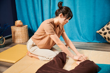 Masseuse making thai yoga massage. Woman therapist doing traditional massage treatment for female...