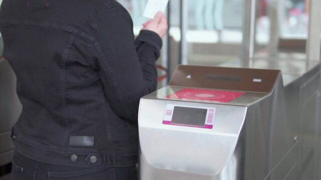 Detail of a woman passing the ticket in a turnstile at the train station in a European city