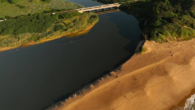 Aerial view of lush greenery, winding river, and bridge over water, umhlanga, kwa zulu natal, south africa.