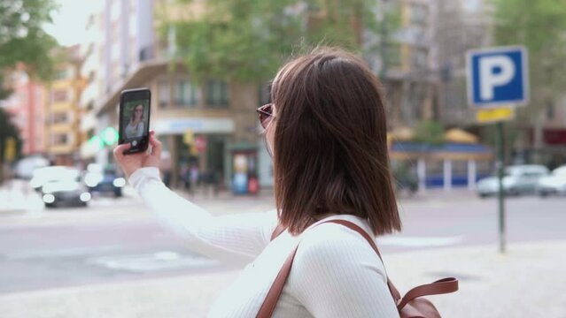 A tourist takes out her phone to take photos while visiting a European city