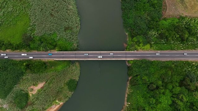 Aerial view of vehicles on bridge over river with lush greenery, North Durban, South Africa.