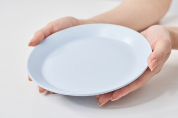 空のお皿を持つ女性の手元
