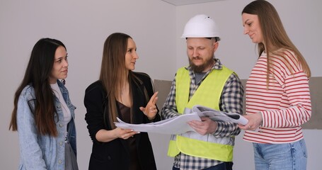 Interior designers and foreman review apartment renovation plans. Focused team discussion on...