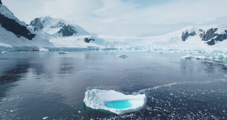 Melting blue water iceberg float in Antarctica ocean bay, aerial panorama. Ice floe drift cold...