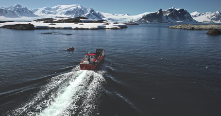 Tourism expeditions to Antarctica. People travel South Pole. Tourists on red boat yacht sailing...