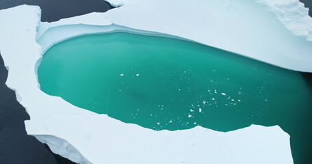 Antarctica iceberg turquoise water close up top down view. Massive glacier floating polar ocean...