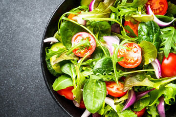 Salad in black bowl at dark background. Healthy green vegetable salad, diet menu. Top view.